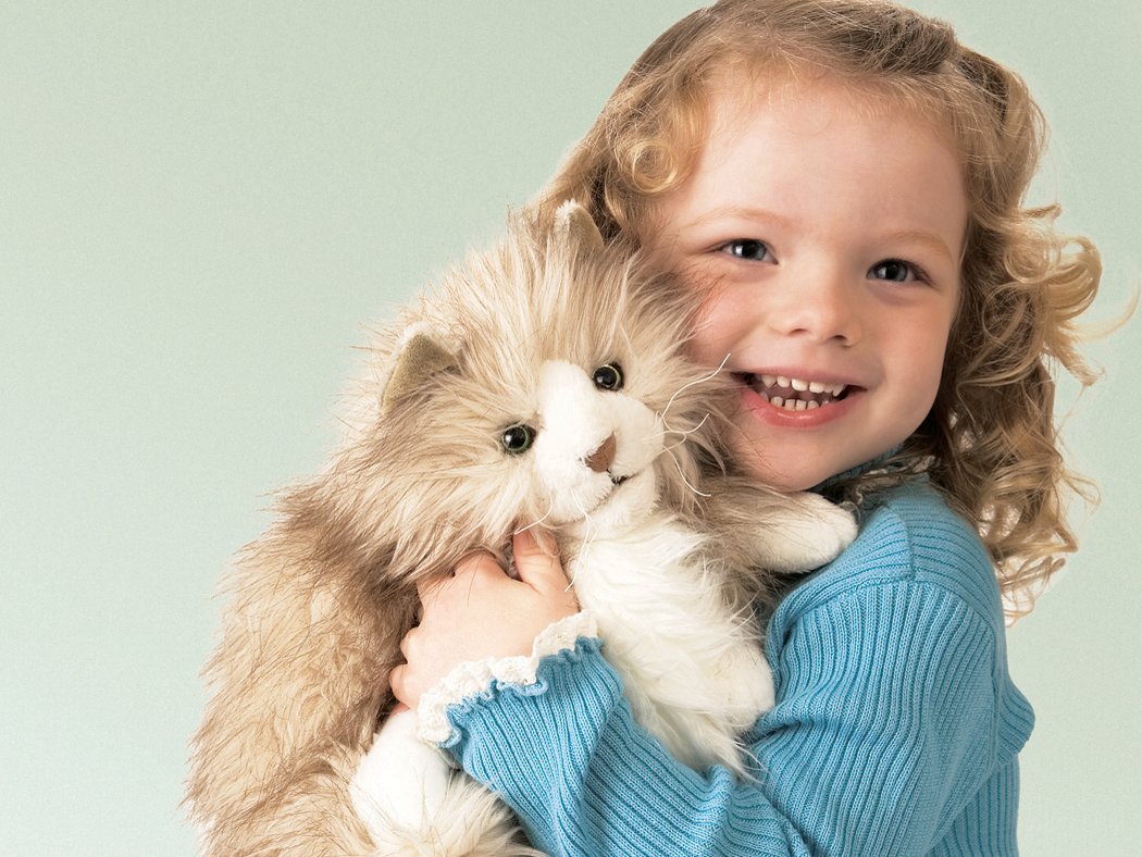 Mädchen hält die Folkmanis-Handpuppe Flauschige Katze im Arm